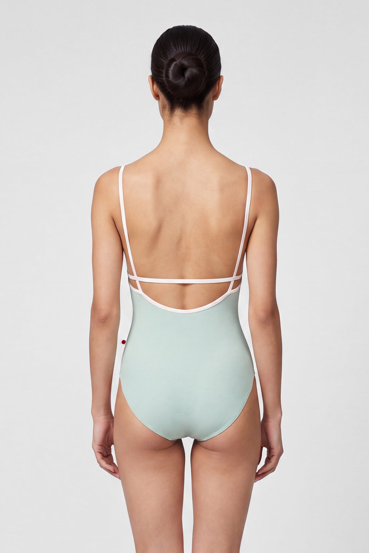 AI-generated model. Heather leotard, pale sage-grey with thin blush straps and neckline trim.