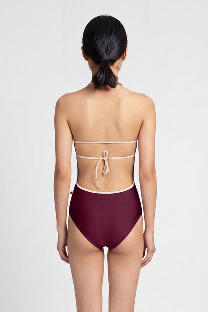 AI-generated model. Kate leotard, deep-burgundy with a cream-trimmed halter neckline and open back.