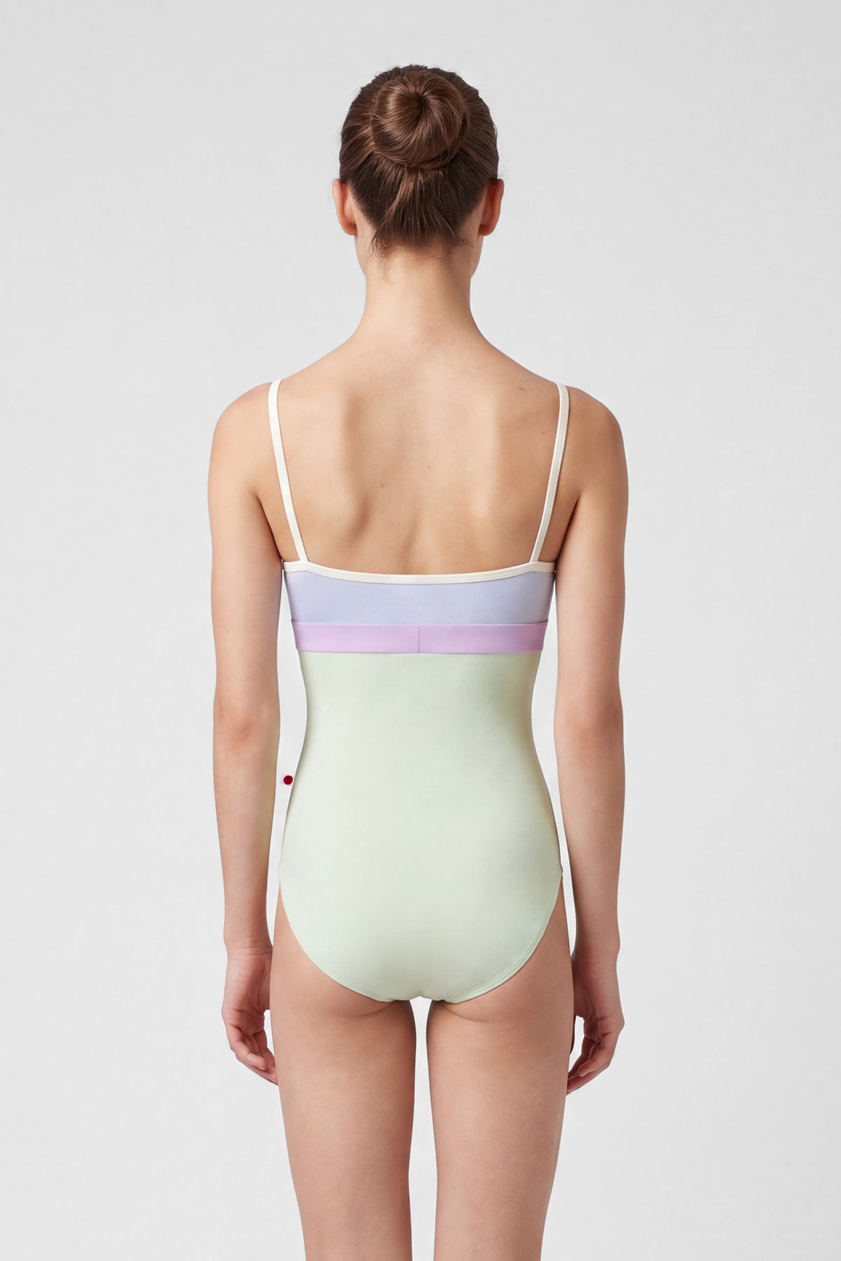 AI-generated model. Zoe leotard, lilac velvet V-neck bodice with a pistachio body and lilac waistband, thin cream straps.