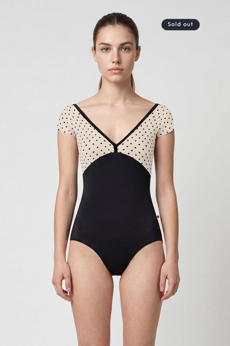 AI-generated model. Alicia leotard, cream polka-dot cap-sleeve bodice with black V-neck trim and black body.