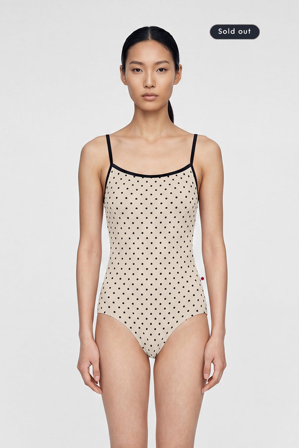 AI-generated model. Daniela leotard, all-over cream polka-dot with thin black straps and black neckline trim.