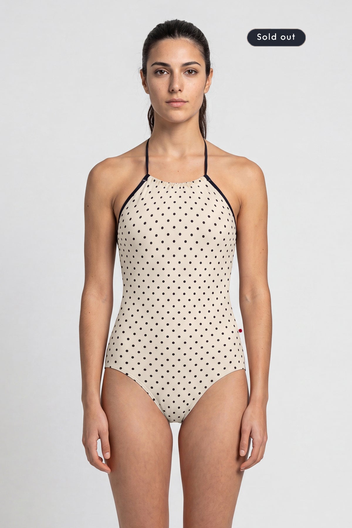 AI-generated model. Monique leotard, all-over cream polka-dot with a black halter neckline.