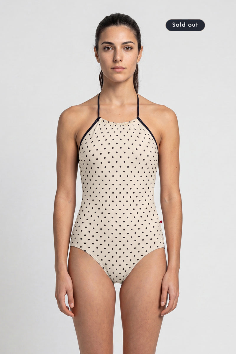 AI-generated model. Monique leotard, all-over cream polka-dot with a black halter neckline.