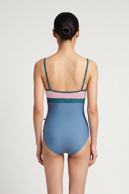 AI-generated model. Zoe leotard, dusty-rose bust and blue-grey body with a teal waistband and thin teal straps, V-neck.