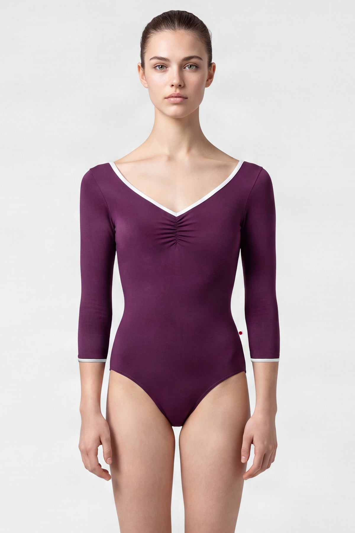 AI-generated model. Anna leotard, aubergine-purple with a ruched V-neck, white trim and three-quarter sleeves.